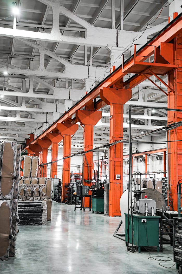 Spacious industrial factory hall with vibrant orange pillars and machinery, ideal for production themes.